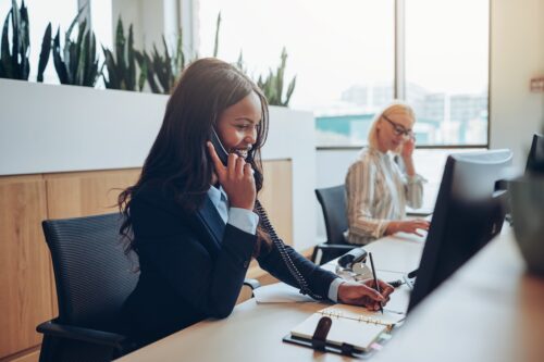 business woman using telephone system for office while working on computer