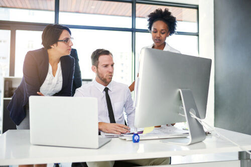 Three coworkers looking at a computer screen