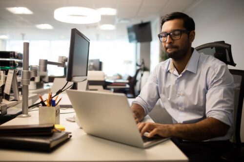 Concentrated businessman working on laptop while sitting at desk in office