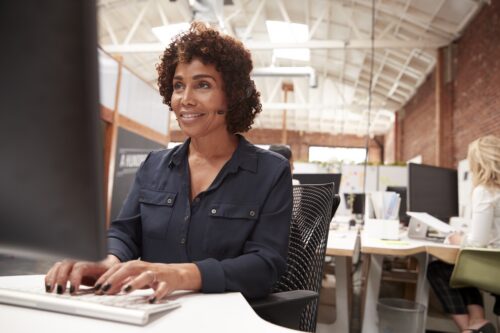 woman working on computer in office while on phone with customer